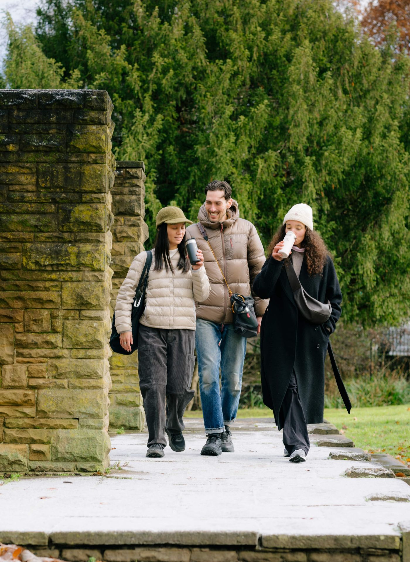 Three people walking in a frosty park, drinking from Stanley flasks