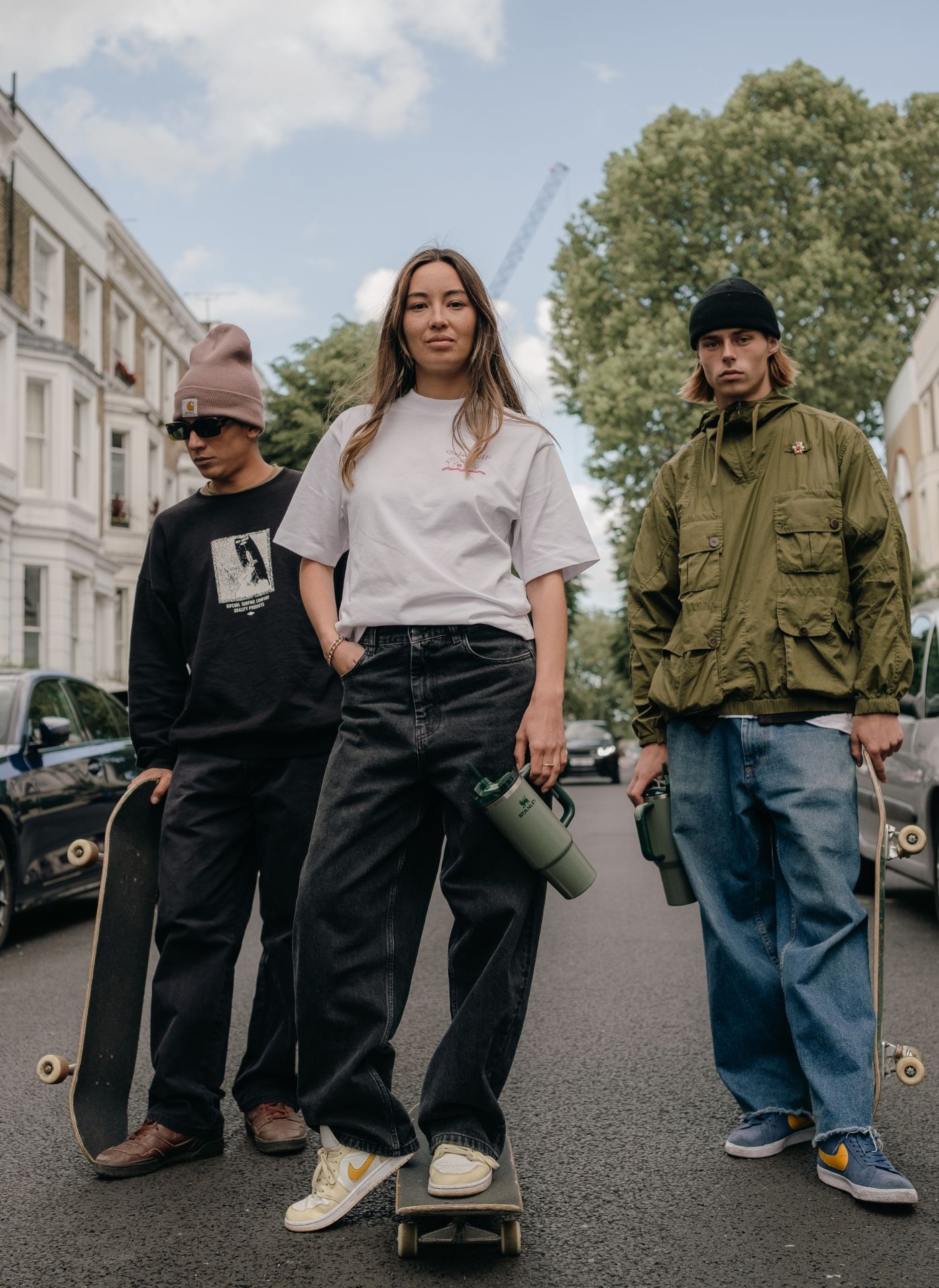 Three people stood in the middle of the road, holding skateboards and Hammertone Green Quenchers