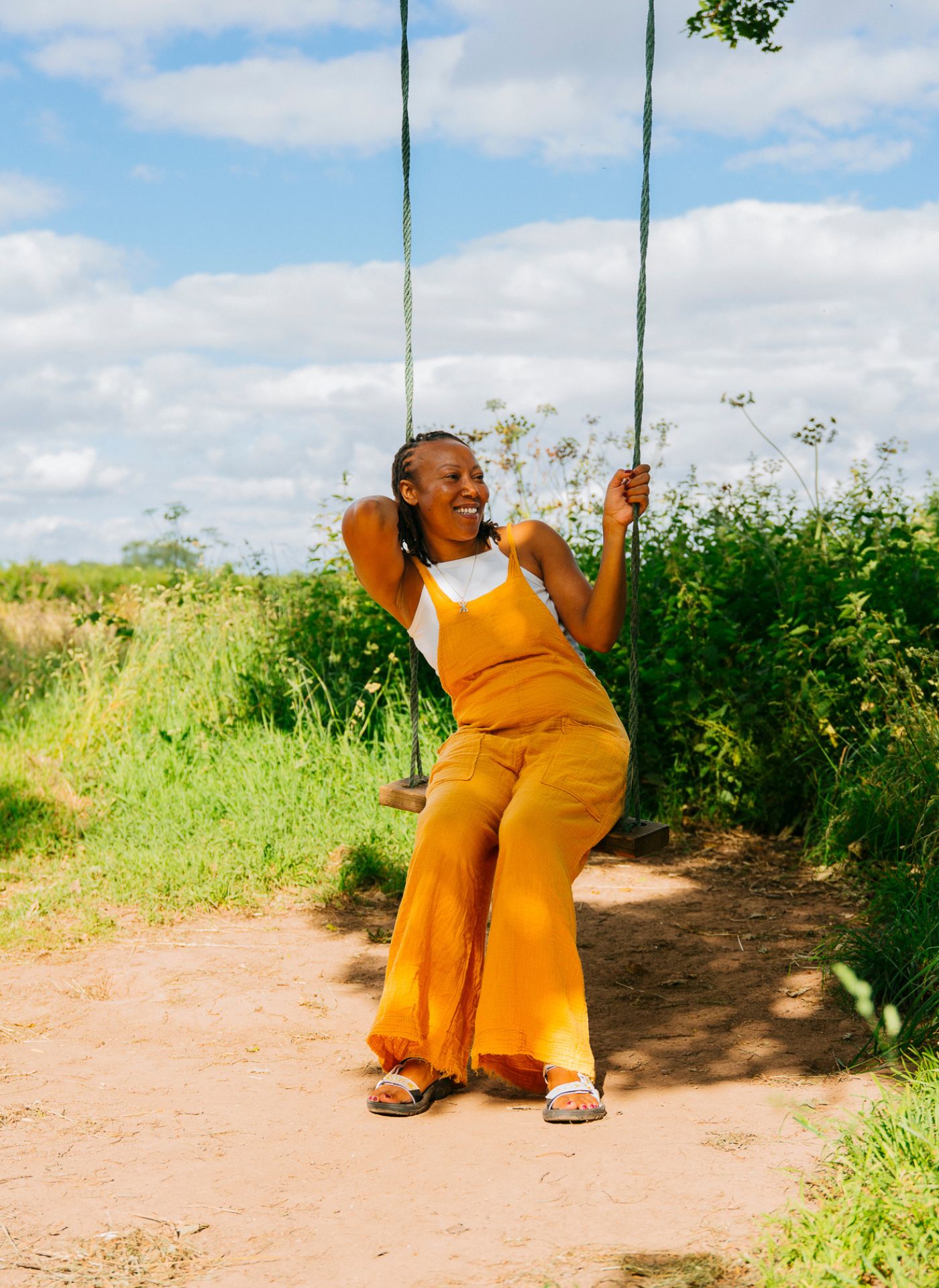 Rhiane Fatinikun sitting on swing wearing Teva sandals