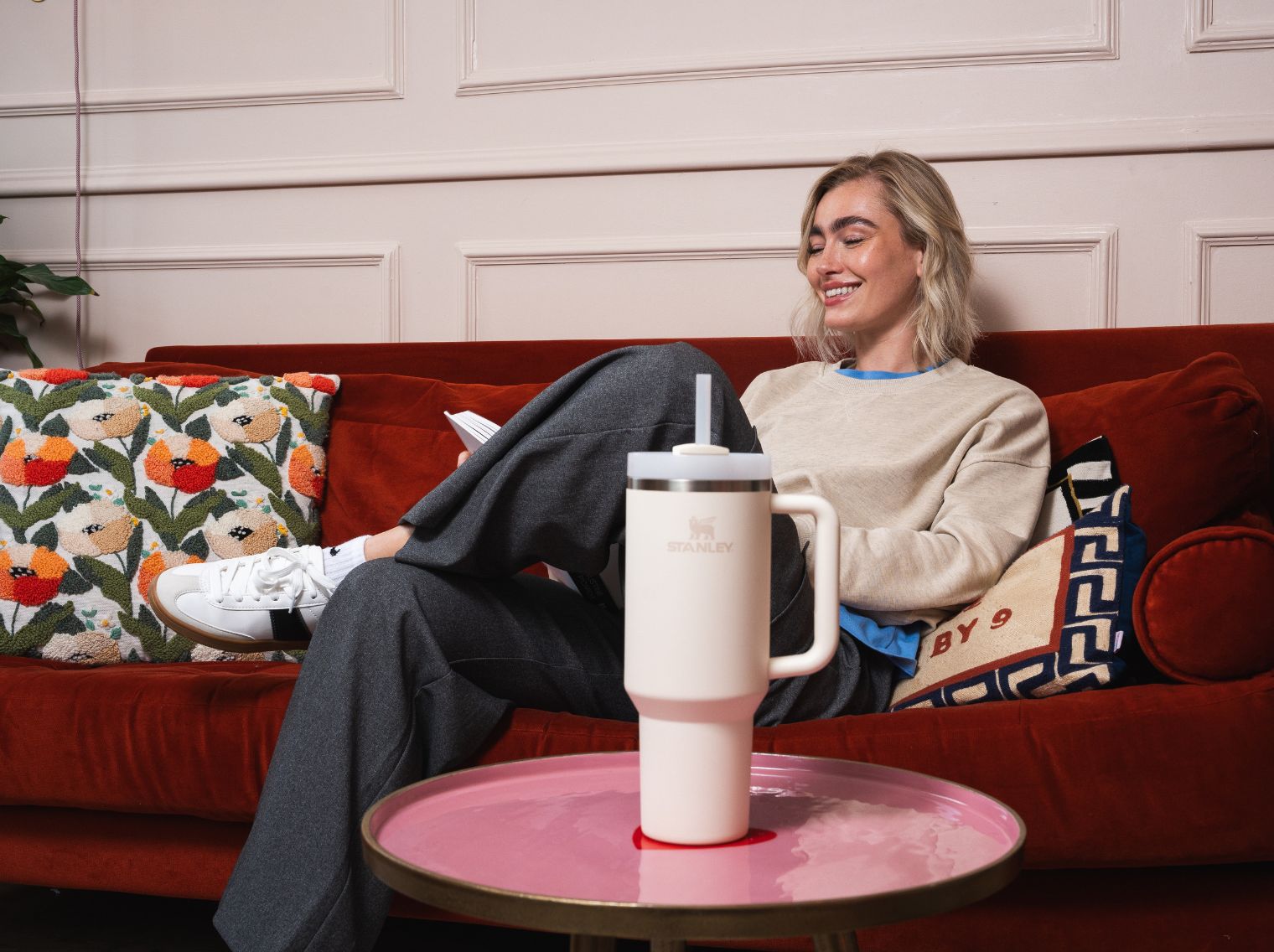 Woman sat on sofa with Stanley Quencher in foreground. Hero image for Stanley Create photoshoot