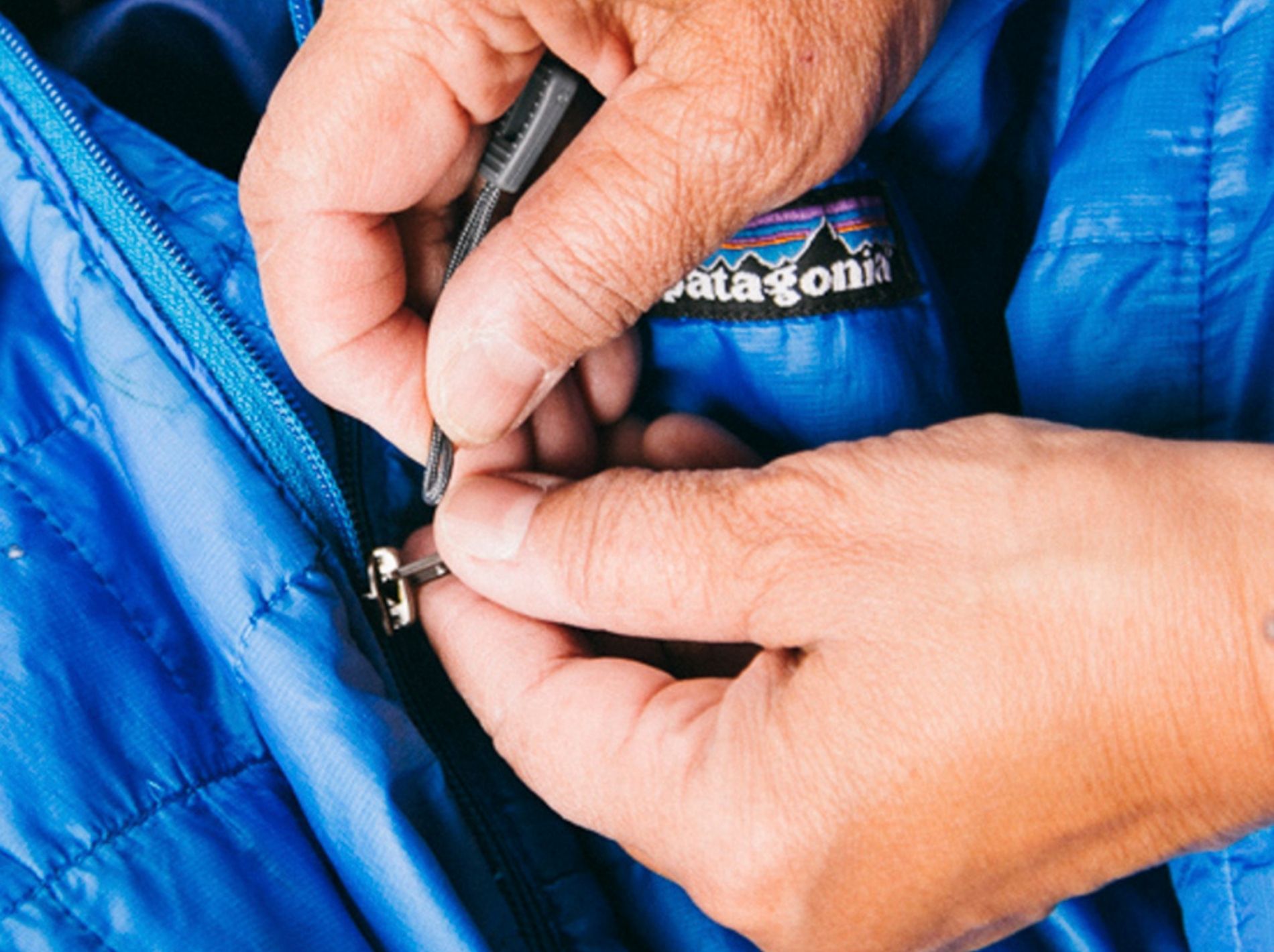 Close up of hands repairing a zip on a Patagonia jacket