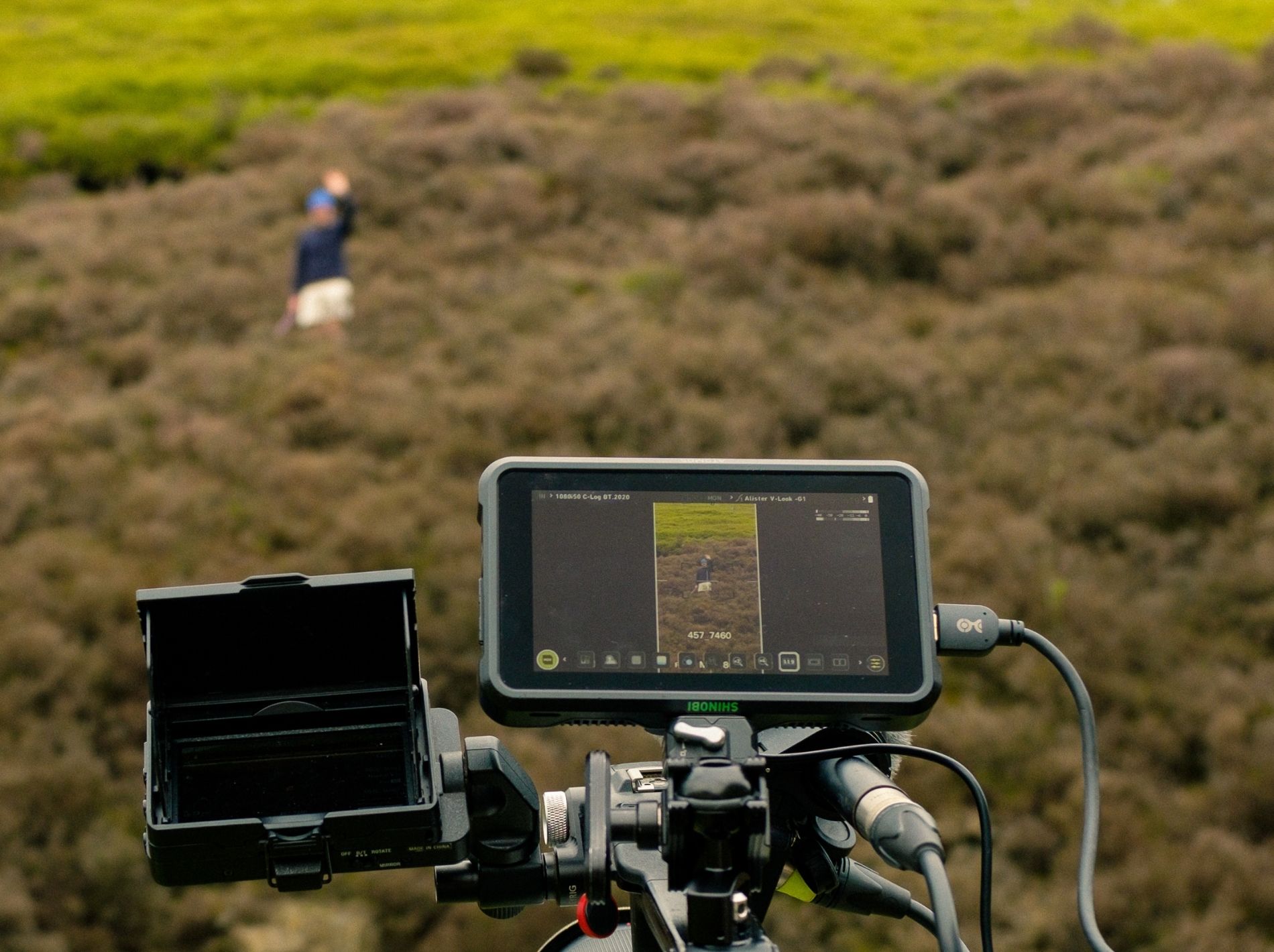 Foreground features the screen of a camera. Background shows moorland